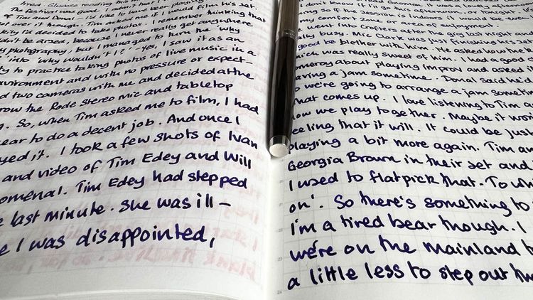 Two hand-written pages with a fountain pen on top. 